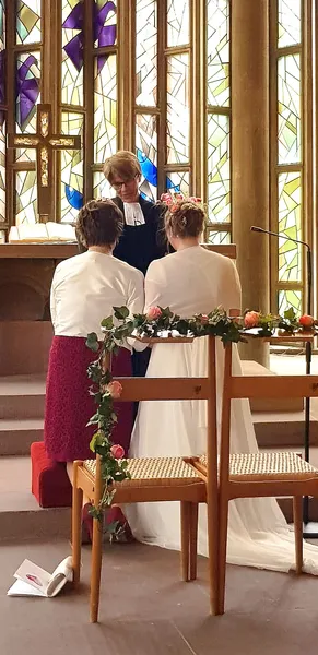 Ein gleichgeschlechtliches Paar wird in einer Kirche von der Pfarrerin gesegnet